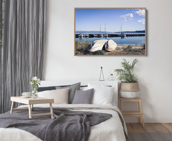 A framed photographic print of alonnah bruny island tasmania showing two white boats on grassy shore under blue sky
