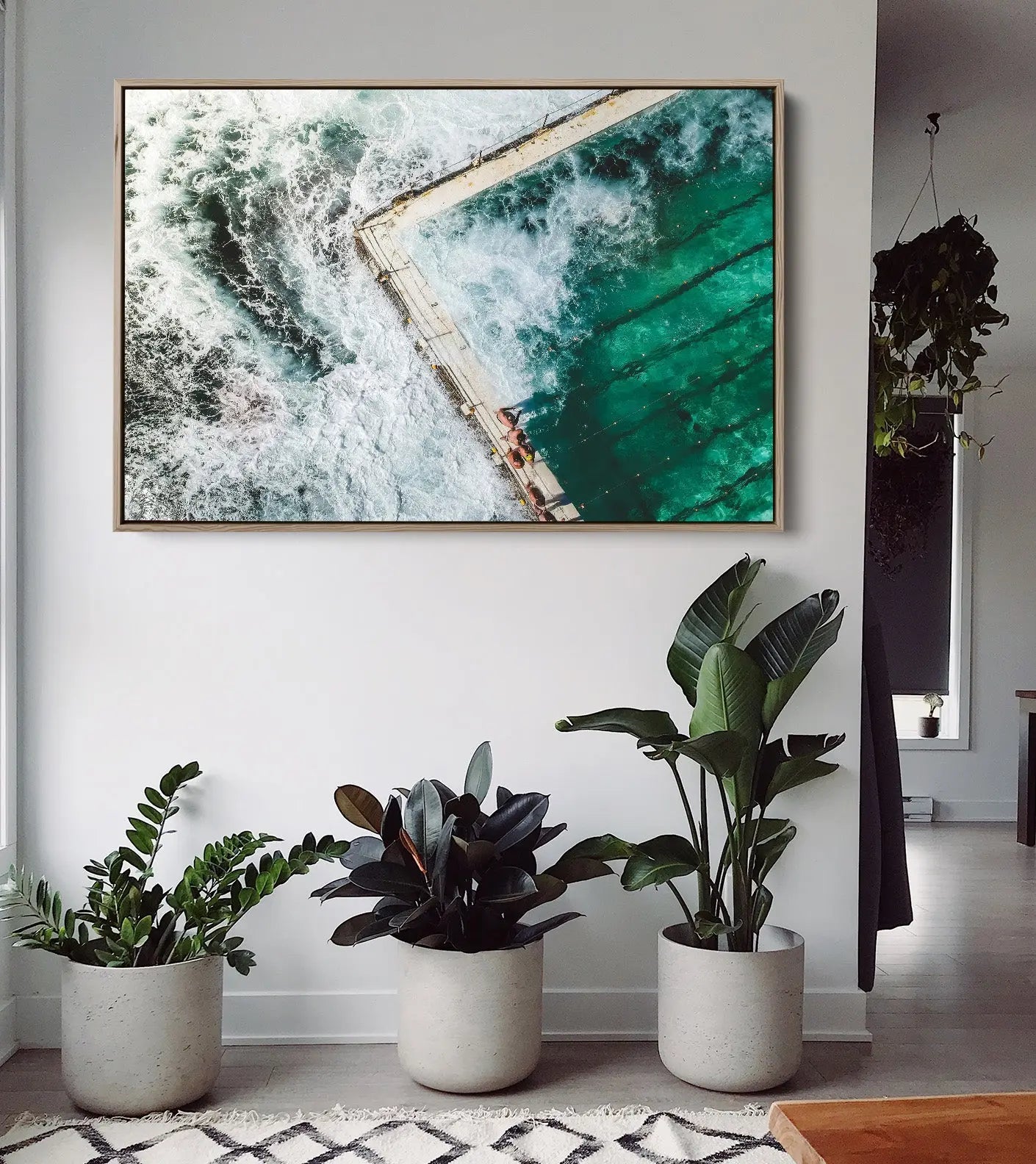 A framed fine art print of a turquoise ocean pool with white waves in a gold-colored frame for ocean swimming decor
