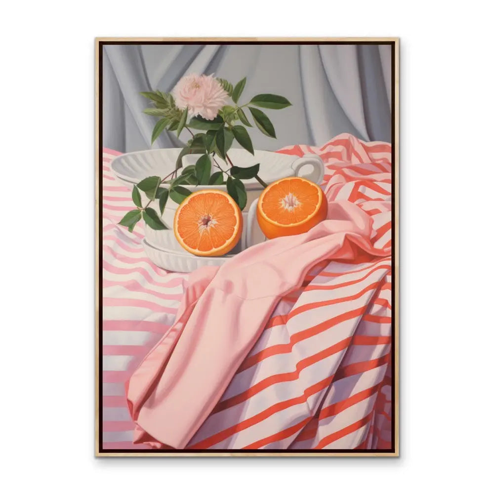 A framed still life artwork of cut orange halves and a pink rose in a white ceramic bowl on a striped tablecloth