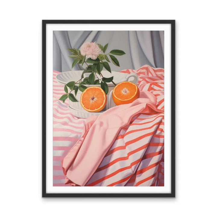 A framed still life painting of a white ceramic bowl with cut orange halves and a pink rose on pink striped fabric