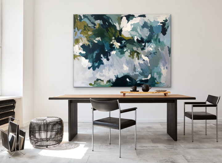 A large dappled lights in the rainforest green and blue abstract canvas print by edie fogarty hanging above a wooden table
