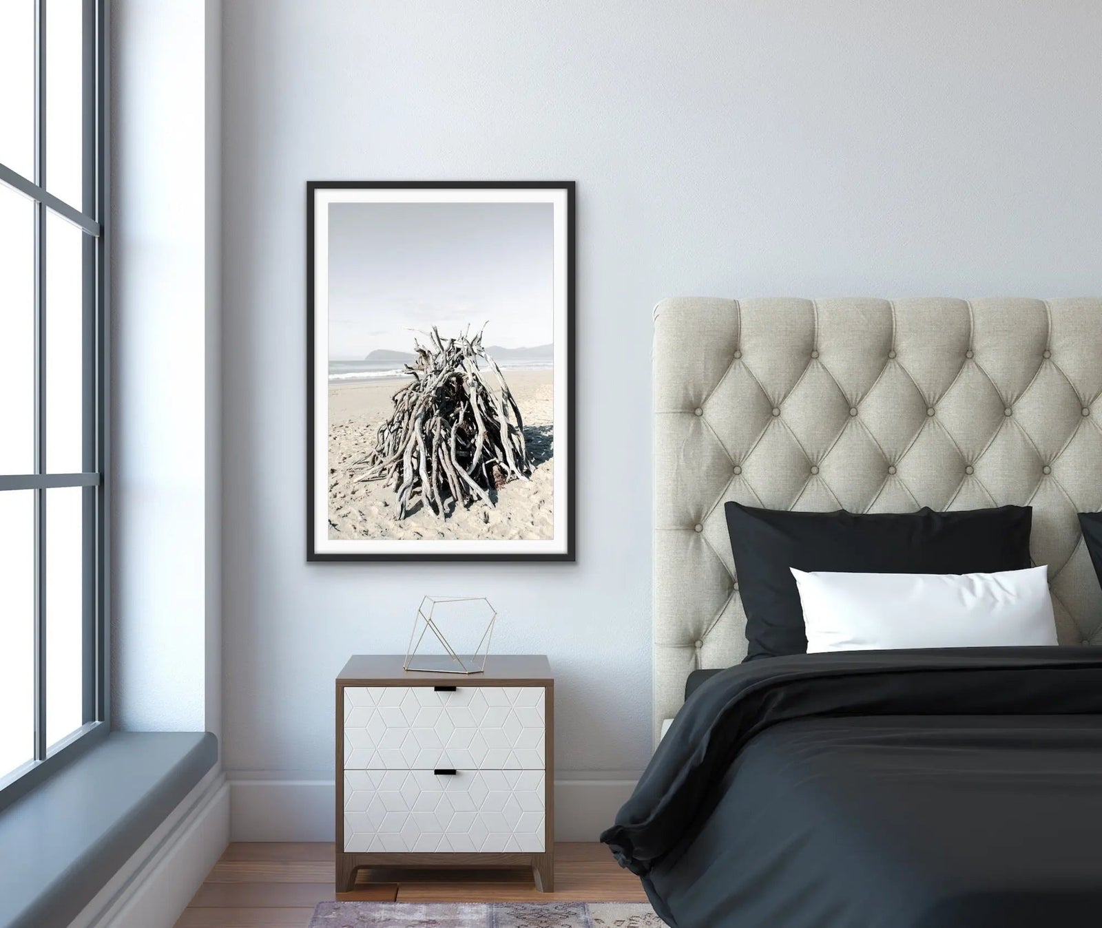 Black-framed photographic print of monochrome driftwood pile on beach by edwina cameron titled driftwood on the beach