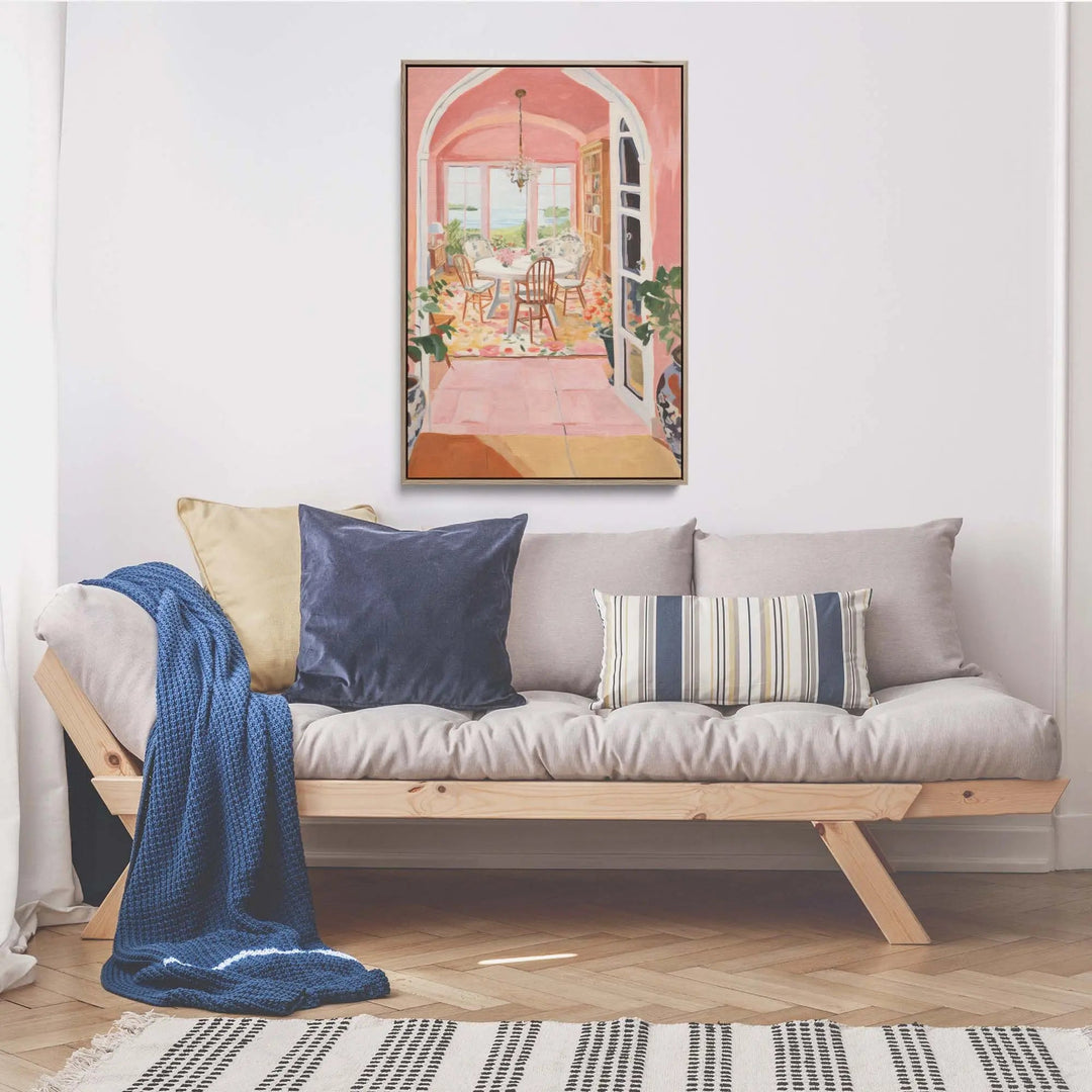 A framed pink and white still life stretched canvas print with a wooden frame hangs above the sofa