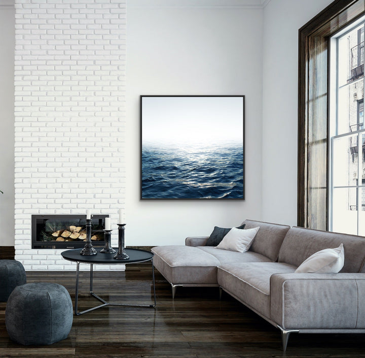 A framed canvas print of moonlit ocean with deep blue waves and soft white horizon in a sleek black frame