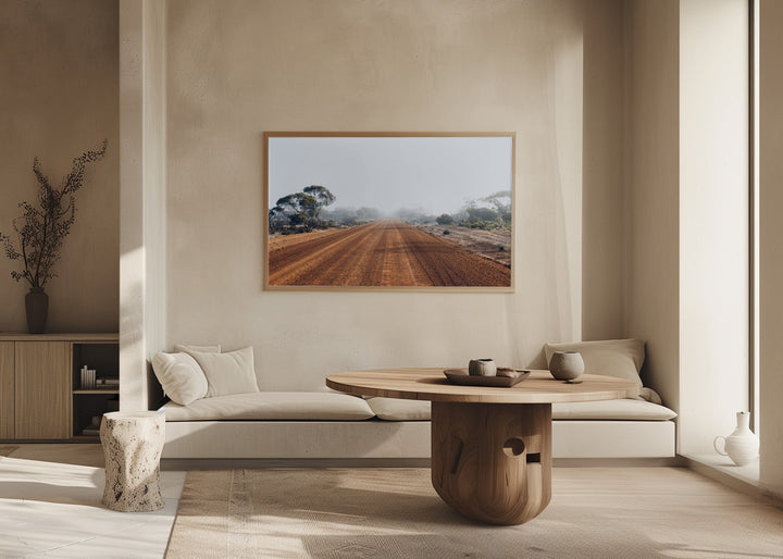 Minimalist wooden framed photographic print of a misty red dirt road with sparse trees in an australian outback landscape