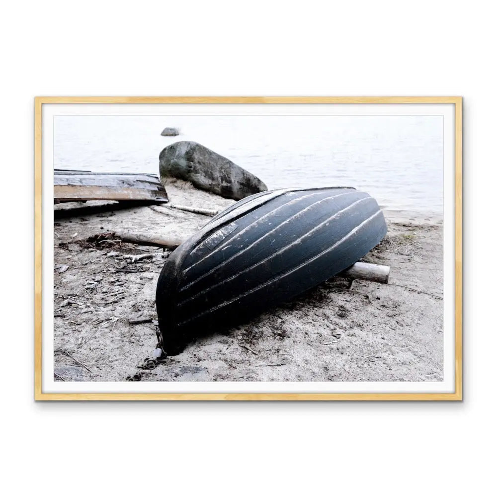 Rowboat on the shore stretched canvas photographic print of a black ribbed canoe resting on a sandy shore