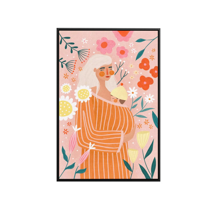 A framed fine art print of a woman in an orange striped dress holding a baby with peach-toned floral background