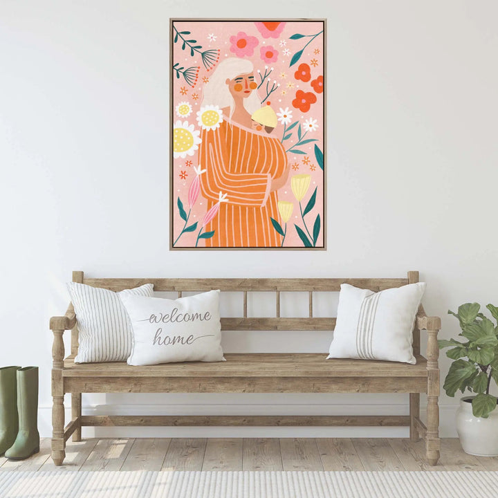 A framed fine art print of a woman in an orange striped dress with colorful flowers on a pink background by be muller
