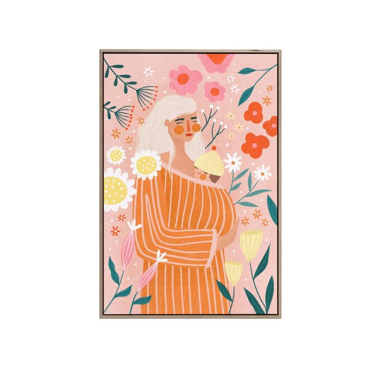 A framed fine art print of a woman in an orange striped dress holding a baby with colorful flowers on a pink background