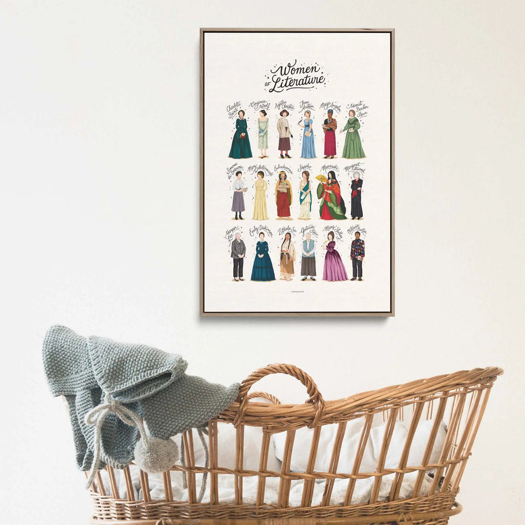 Framed women of literature poster by nour tohme featuring illustrated authors in period attire displayed above wicker bassinet