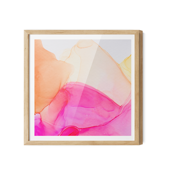 A vibrant abstract alcohol ink painting wall art print in pink peach and yellow in a light wood frame